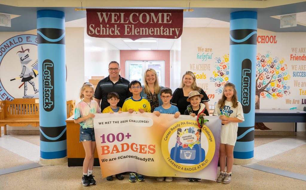 Students and administrators stand with the banner displayed.