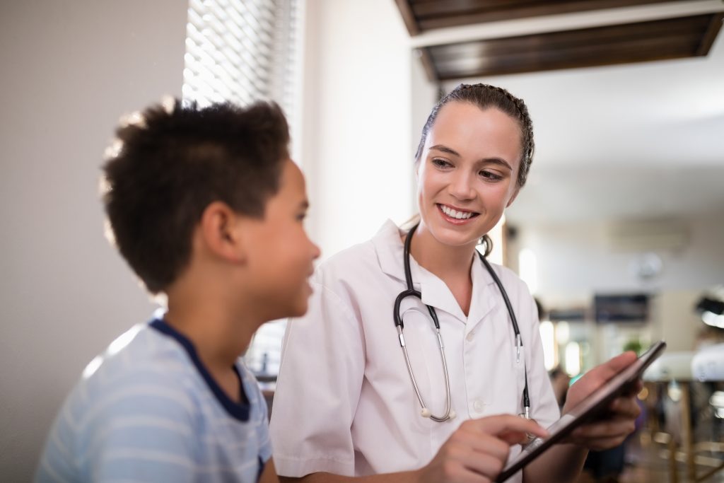 Smiling female nurse showing digital tablet to boy