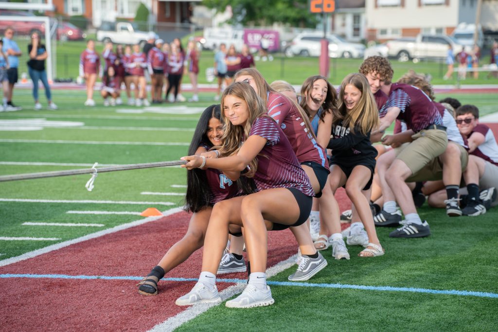 Students engage in a tug-of-war on the sidelines. 