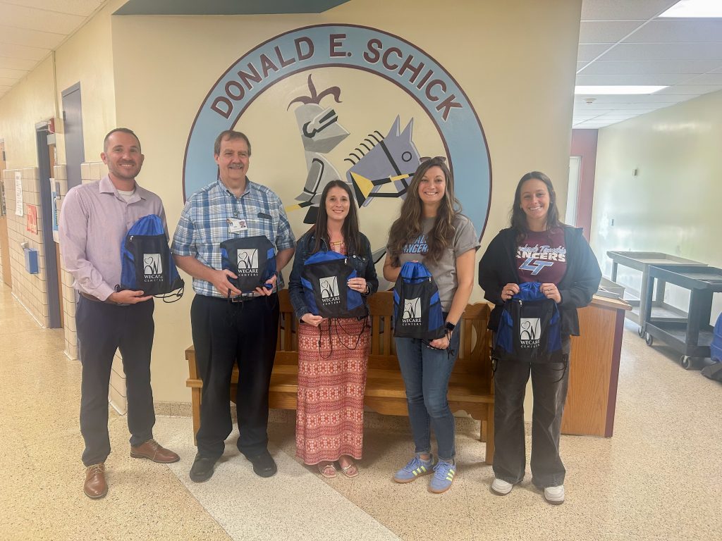 WeCare representatives and Schick admin pose holding a few of the donated bags.